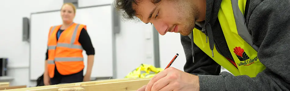 student writing with pencil in carpentry class